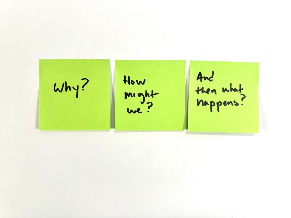 Three green sticky notes on a wall. The first reads, "Why?" The second, "How might we?" and the third, "And then what happens?"